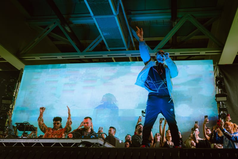 Ali Love with his arm raised on a festival stage, in front of a large screen and the crowd
